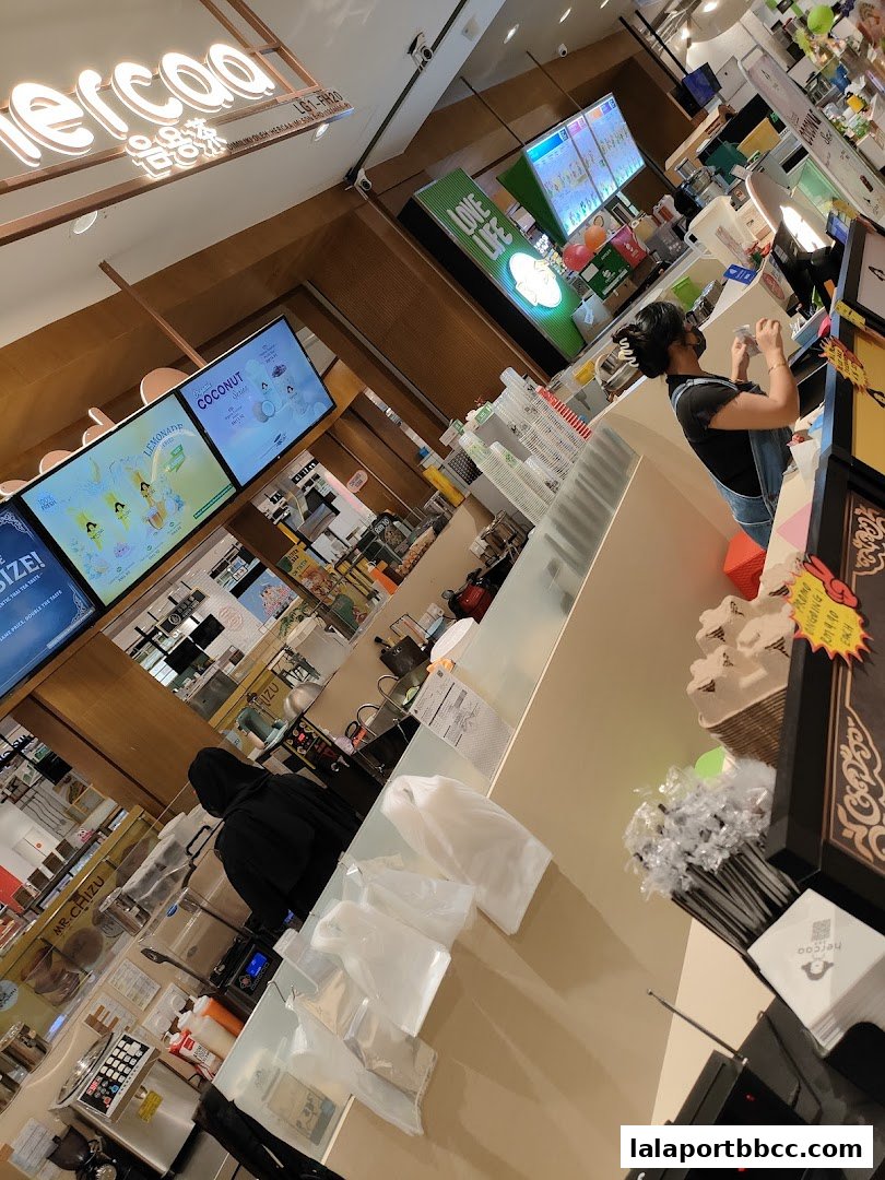 Interior view of a modern beverage shop with digital menus and staff preparing drinks.