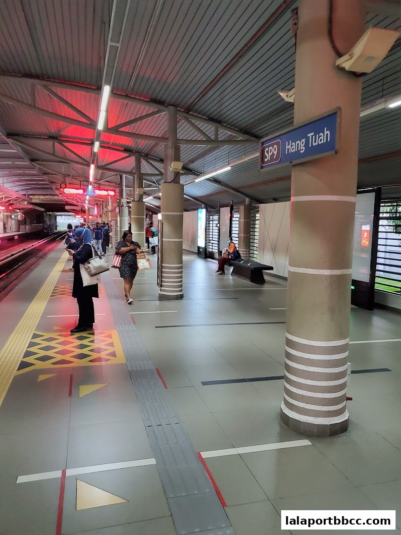 People waiting on a train platform with a sign indicating 'Hang Tuah' station.