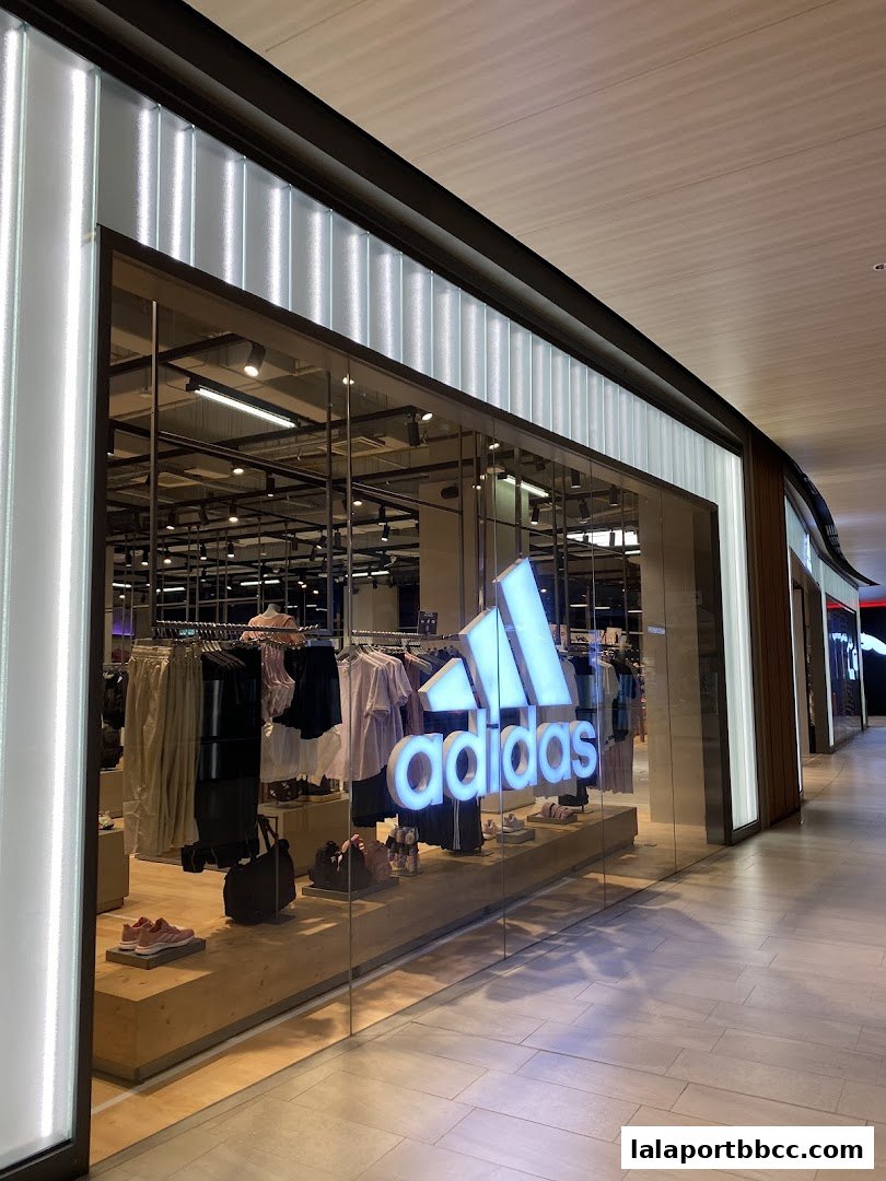The exterior of an Adidas Originals store with its iconic logo and displayed apparel.