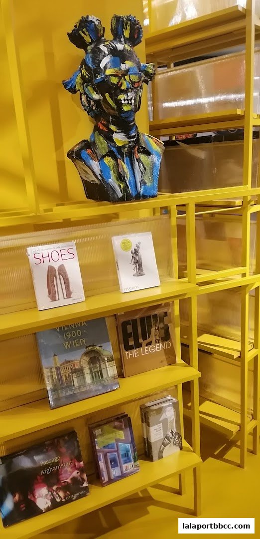 A vibrant yellow display shelf featuring books and a colorful bust sculpture.