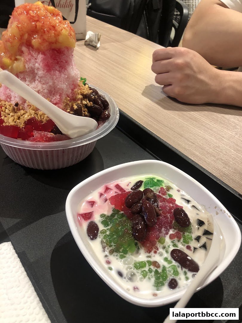 Two bowls of colorful shaved ice desserts with various toppings, including fruits and beans.