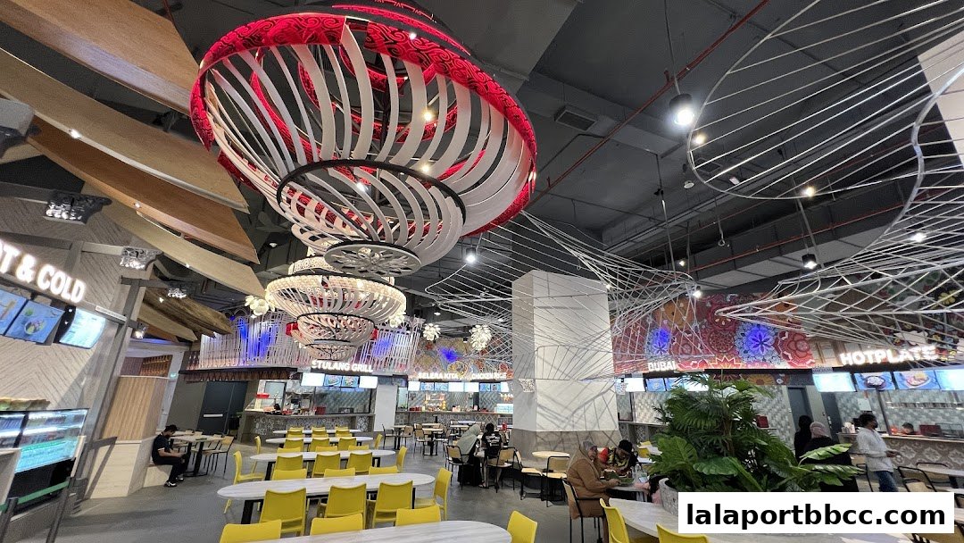 A spacious food court with modern decor, featuring unique hanging light fixtures and various food stalls.