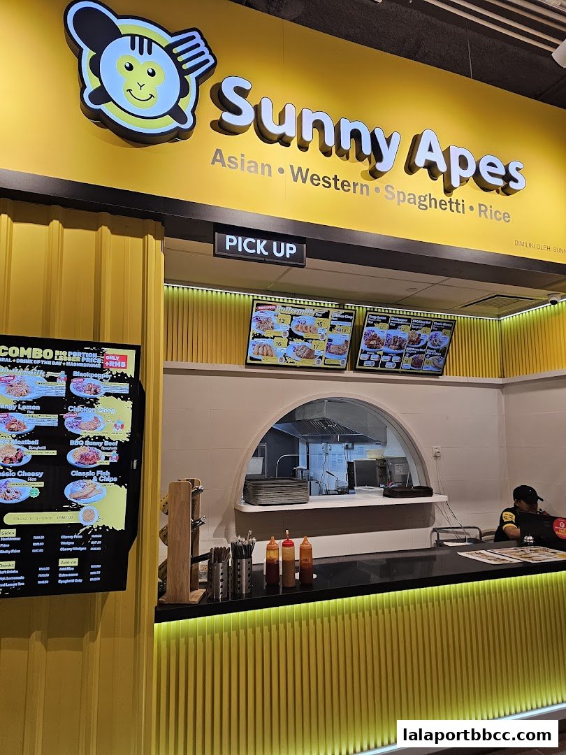 A bright yellow food stall with a prominent 'Sunny Apes' logo and menu displays.