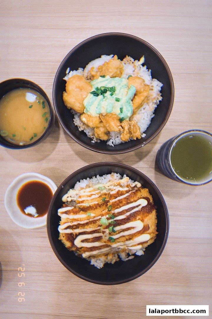 Two bowls of Japanese rice dishes with miso soup and green tea.