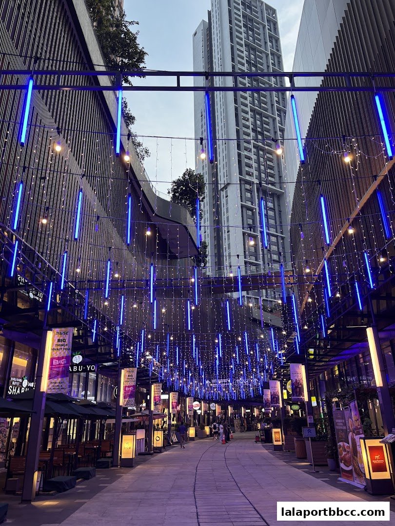 A street lined with shops and restaurants, decorated with blue and white lights.