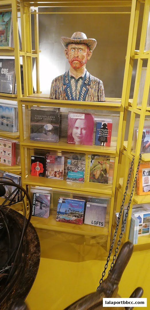 A yellow shelving unit displays books and a bust of Vincent van Gogh.