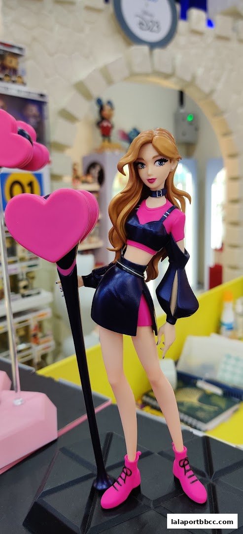 A detailed figurine of a female character with long blonde hair and a pink and black outfit.