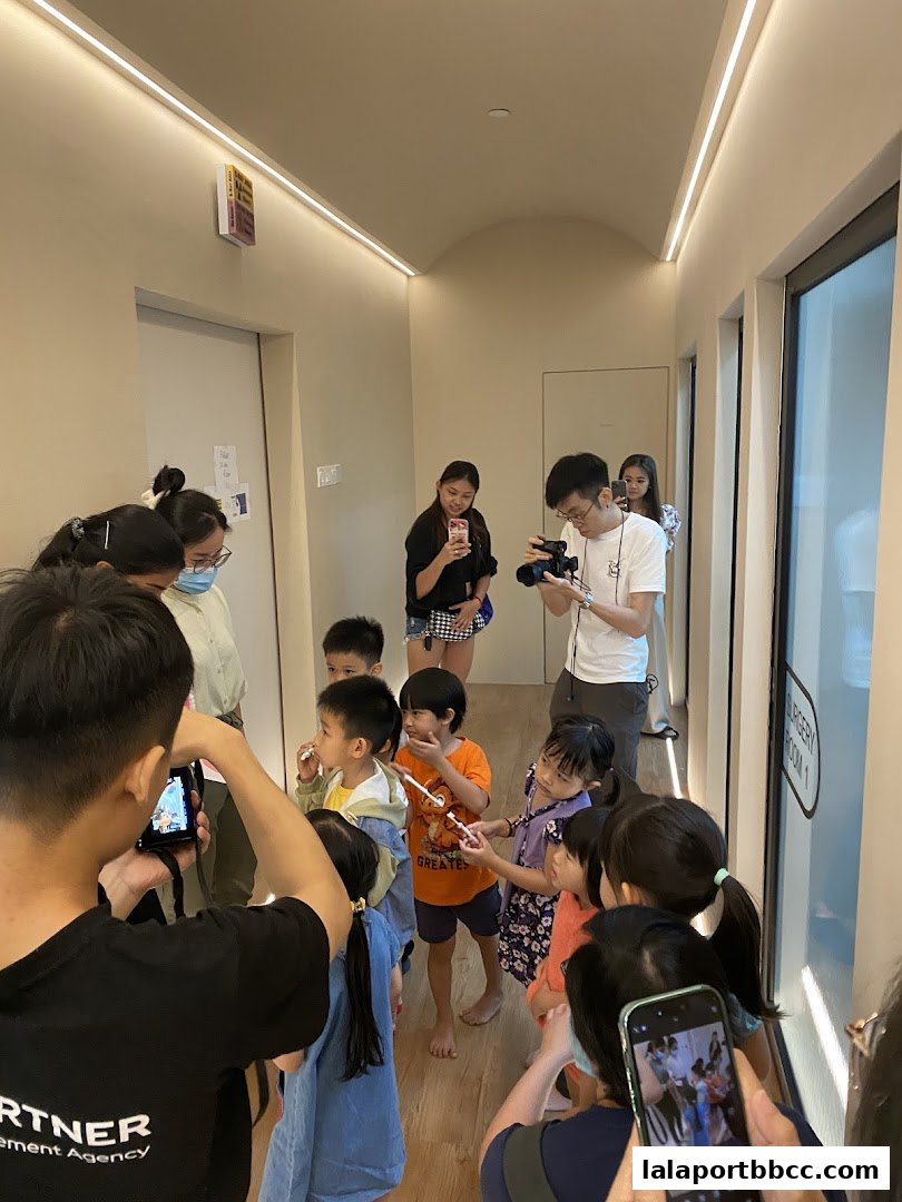 Children and adults gathered in a clinic hallway, some holding toothbrushes and phones.