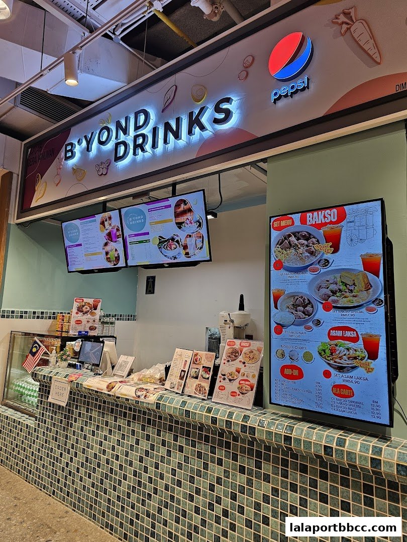 A food stall counter with illuminated signage and digital menus displaying food and drinks.