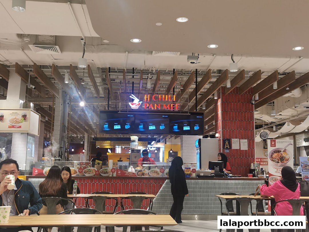 People dining at JJ Chili Pan Mee restaurant in a modern food court setting.