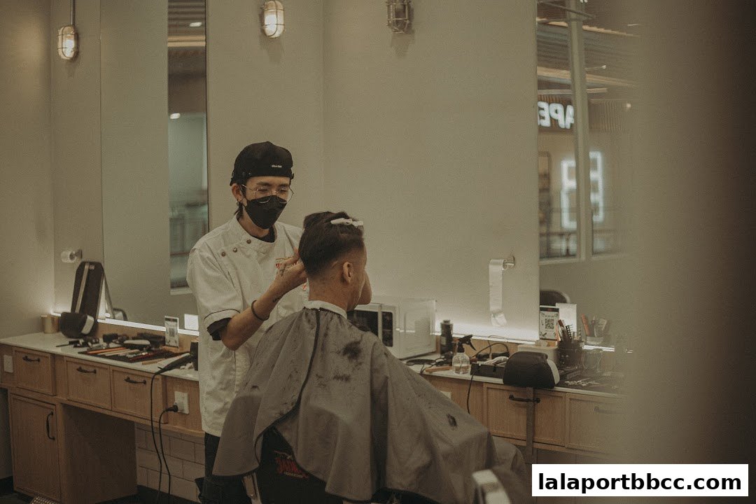 A barber cuts a client's hair in a modern, well-lit barbershop.