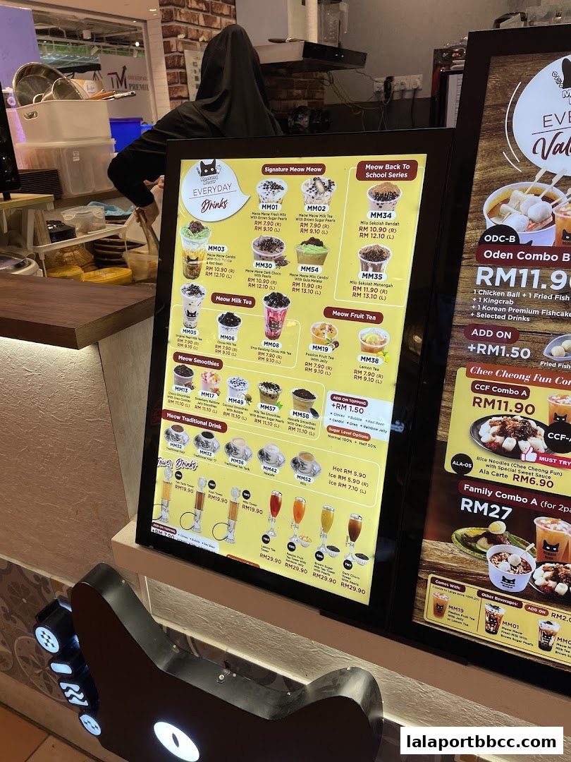A digital menu board displaying various drinks and combo meals from Memang Meow.