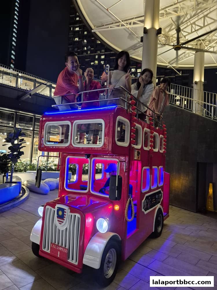 A family poses on a red double-decker bus attraction at night.