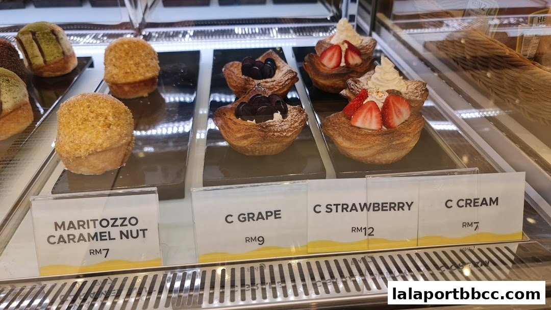 A display case filled with various pastries, including Maritozzo Caramel Nut, Grape, Strawberry, and Cream.