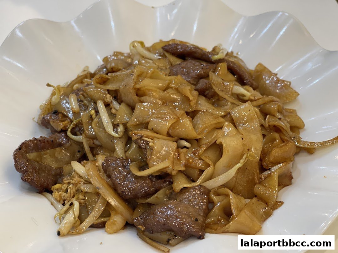 A close-up shot of a delicious plate of beef hor fun noodles with bean sprouts.
