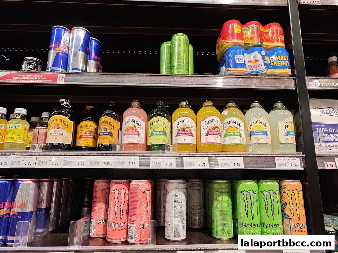 Shelves stocked with various energy drinks and bottled beverages, including Red Bull, Bundaberg, and Monster.