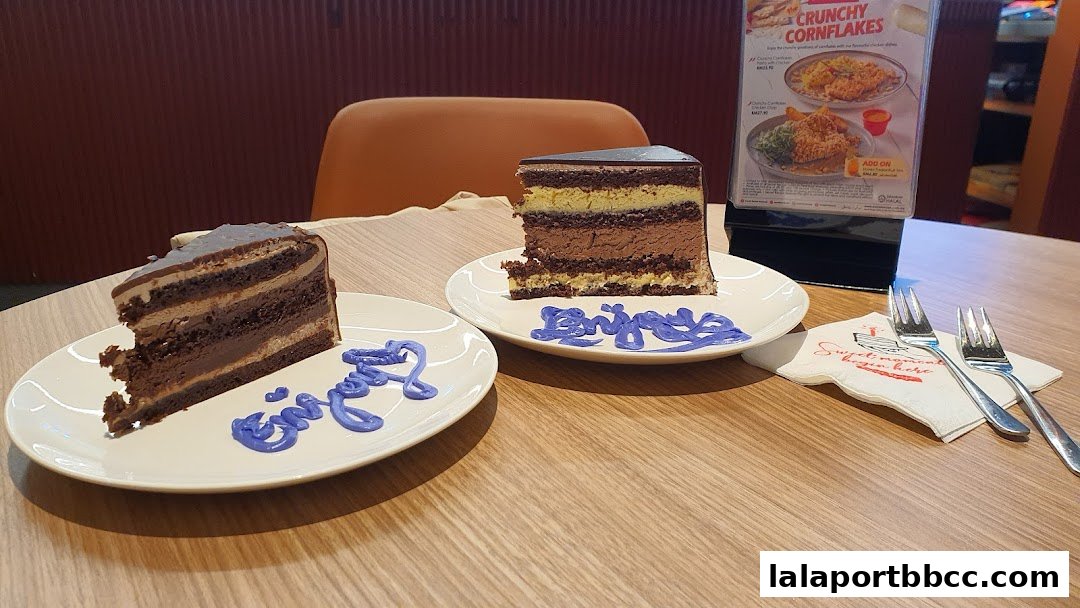 Two slices of layered chocolate cake served on plates with purple icing decorations.