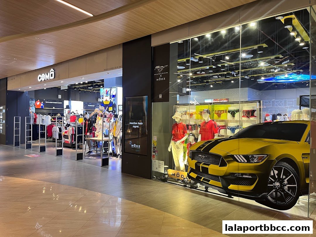 The entrance of a stylish clothing store with mannequins and a yellow sports car display.