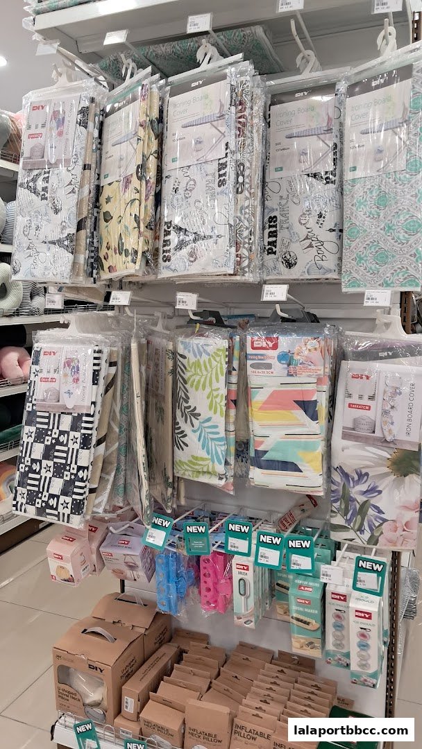 Shelves stocked with various home goods including ironing board covers, pillows, and kitchenware.
