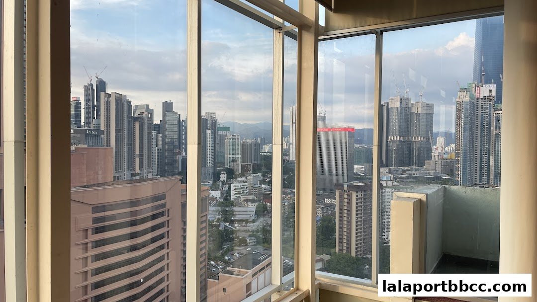 Panoramic view of a city skyline with skyscrapers and construction sites from a high vantage point.