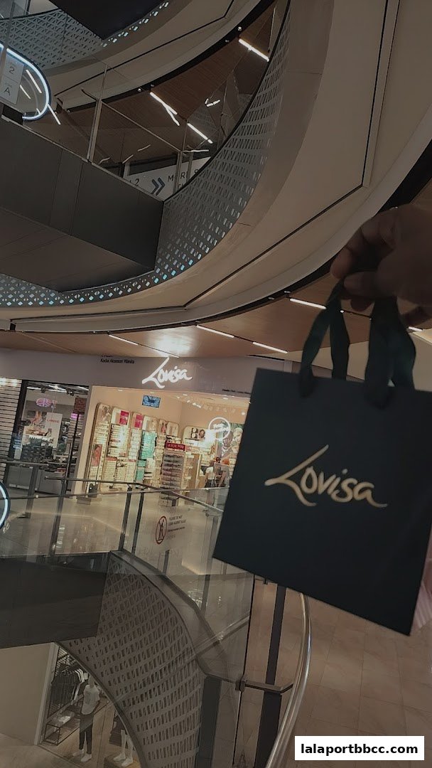 A person holds a Lovisa shopping bag in front of the store.