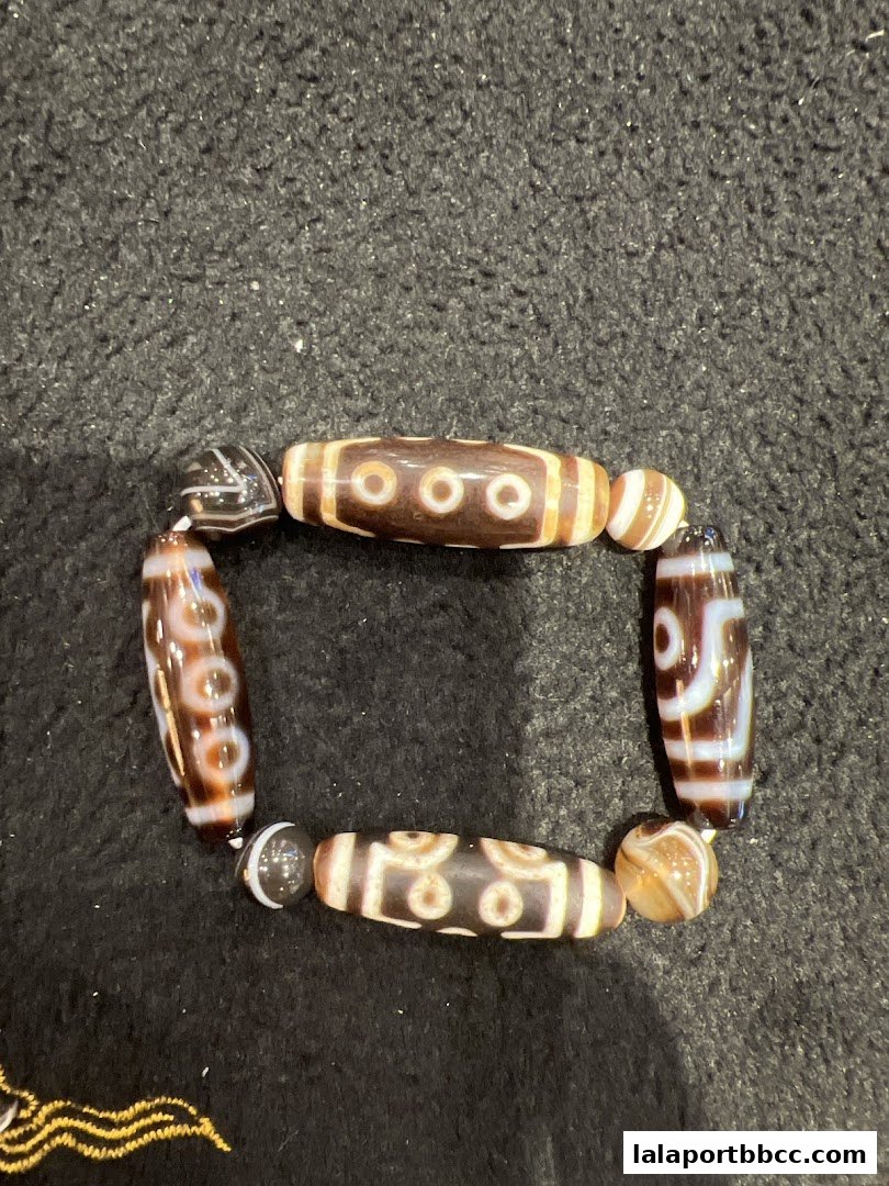A bracelet made of Dzi beads with intricate patterns on a dark textured surface.