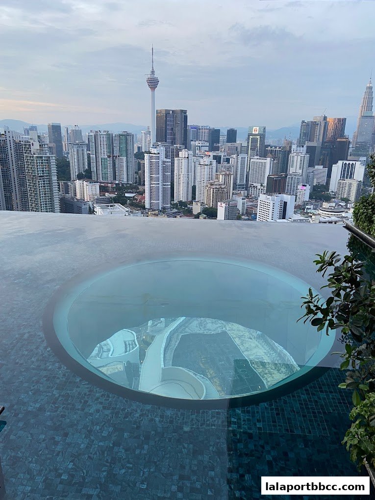 Infinity pool with a glass bottom overlooking a city skyline at dusk.