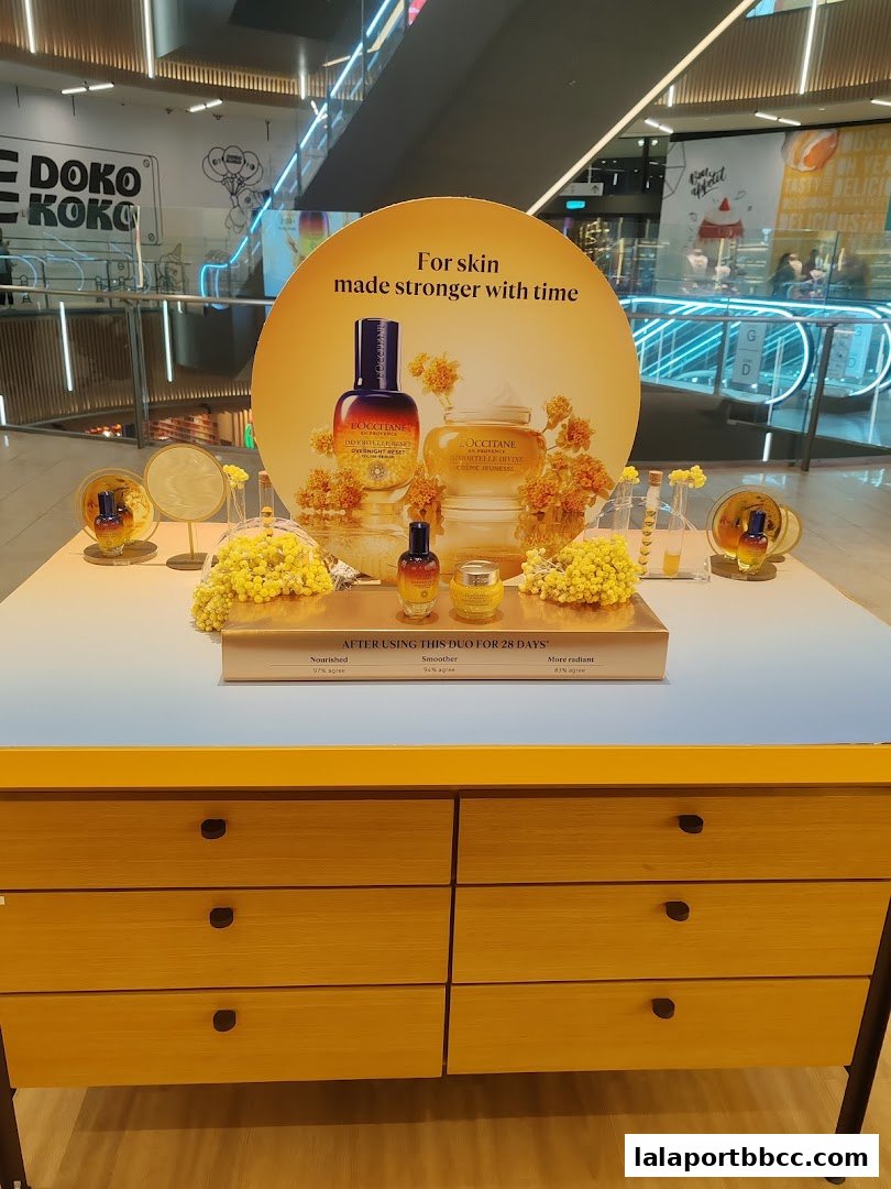 L'Occitane display featuring Immortelle Divine skincare products with a promotional message.