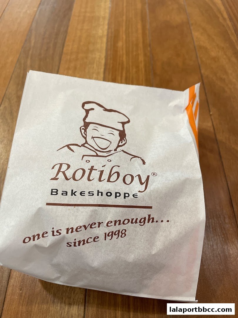 A paper bag from Rotiboy Bakeshoppe with a cheerful chef logo and slogan.