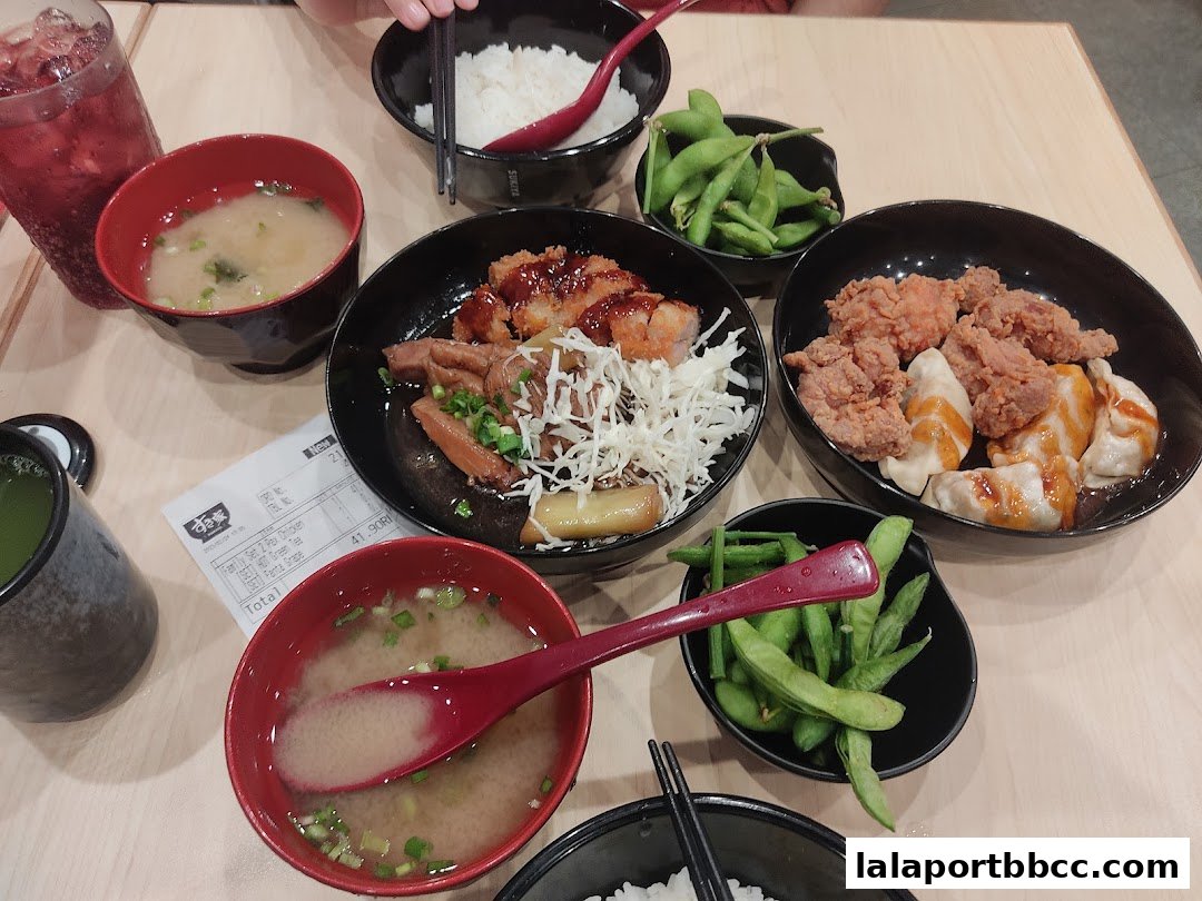 A table filled with various Japanese dishes including fried chicken, dumplings, edamame, and miso soup.
