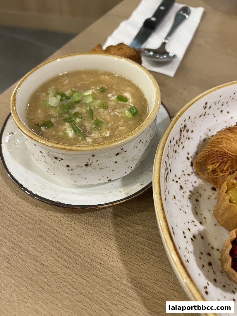 A close-up of a bowl of soup with chopped green onions and a side dish.