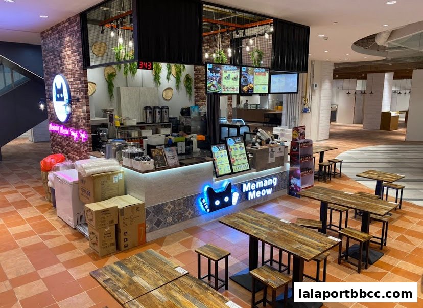 A modern bubble tea shop with seating, featuring a prominent neon cat logo and menu displays.