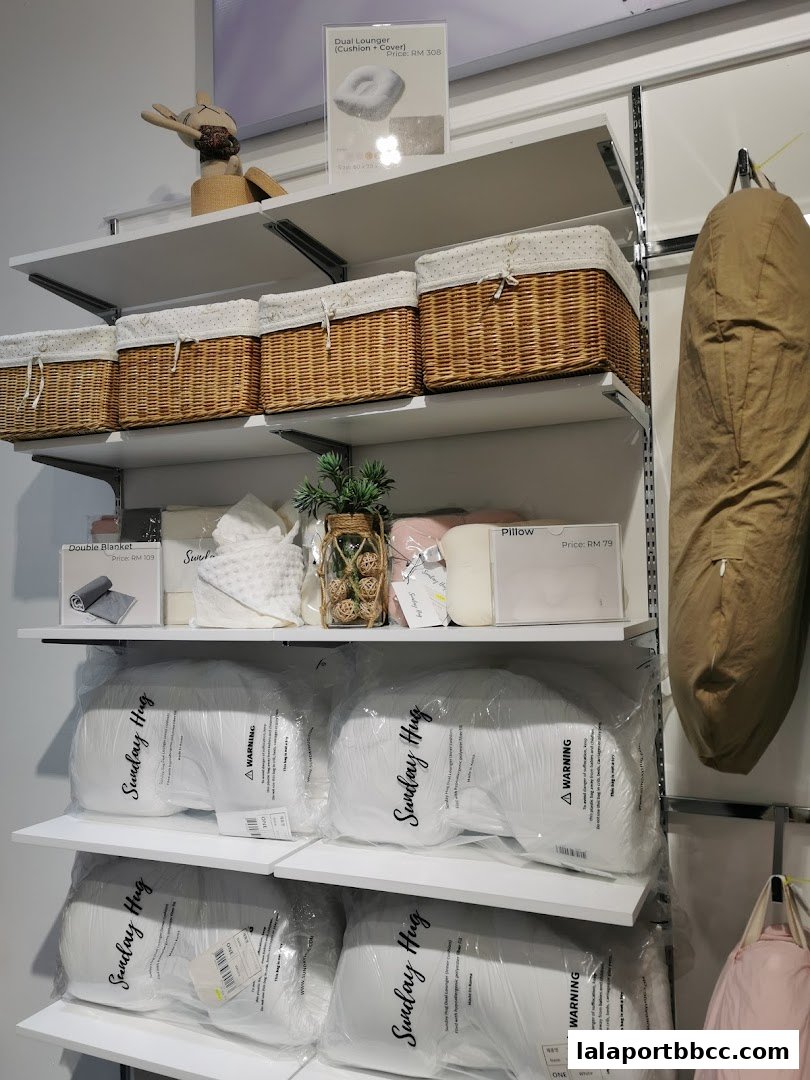 Shelves display pillows, blankets, baskets, and decorative items in a retail store.