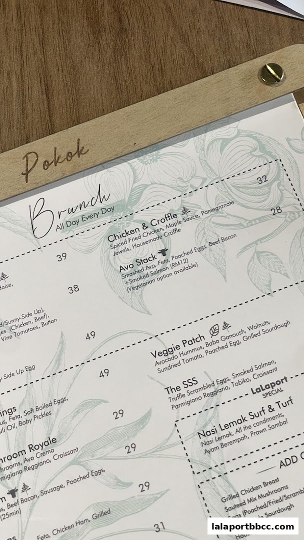 A close-up of a menu from POKOK LaLaport featuring brunch items with prices.