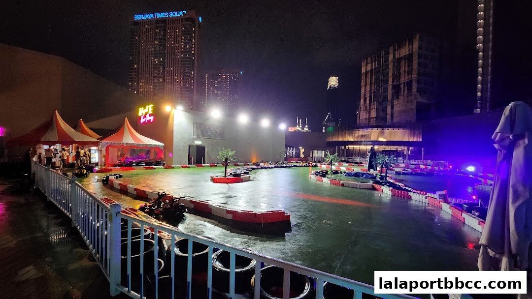 A nighttime view of an outdoor go-kart track with colorful barriers and tents.