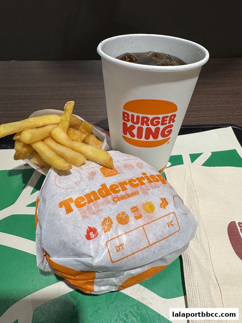 A Burger King meal featuring a TenderCrisp Chicken burger, fries, and a soda.
