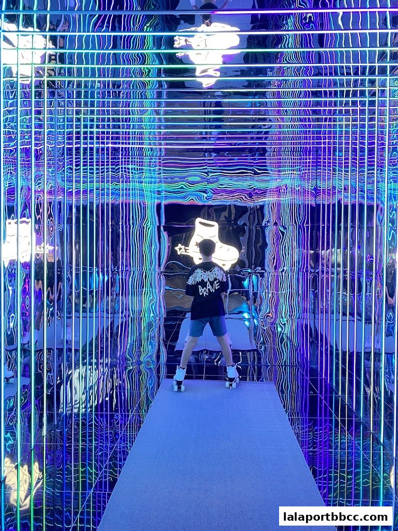 A person wearing roller skates stands in a dazzling tunnel of blue and purple neon lights.