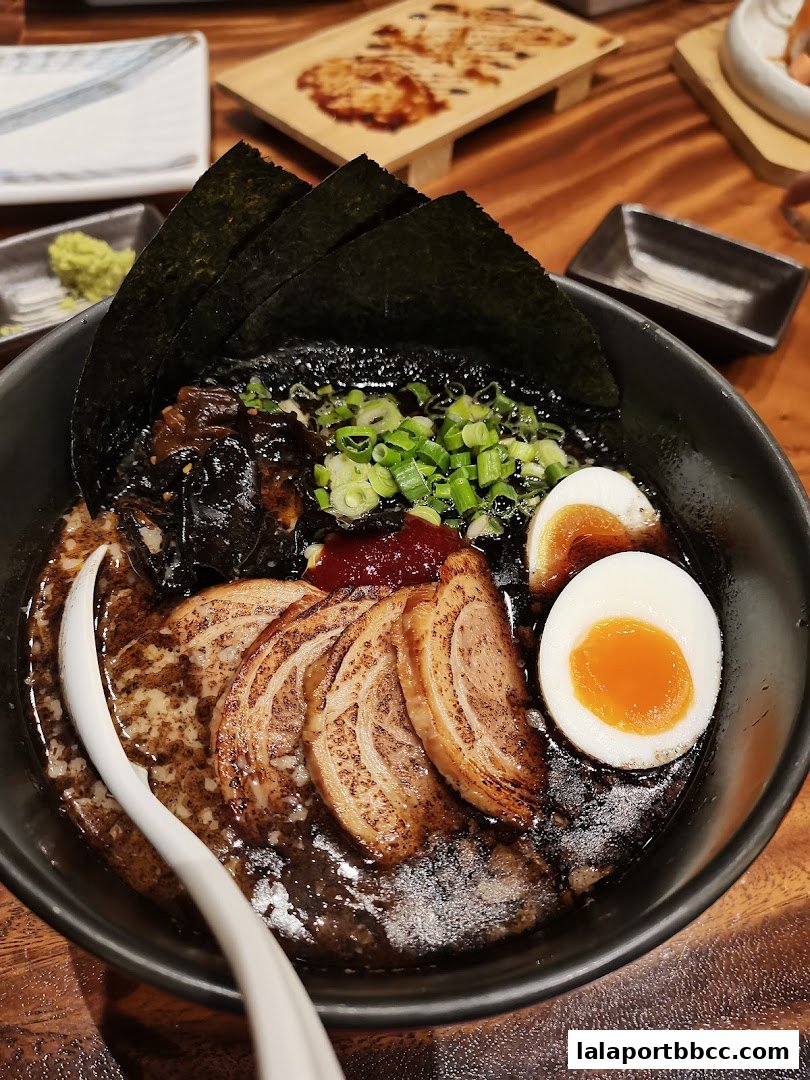A close-up of a delicious bowl of ramen with pork slices, egg, and seaweed.