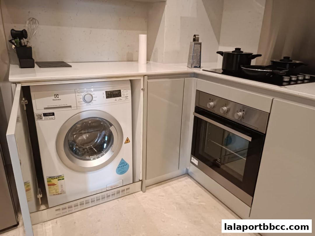 A modern kitchen counter with a washing machine, oven, and stovetop.