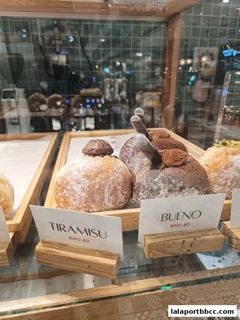 Close-up of delicious donuts with labels 'Tiramisu' and 'Bueno' in a display case.