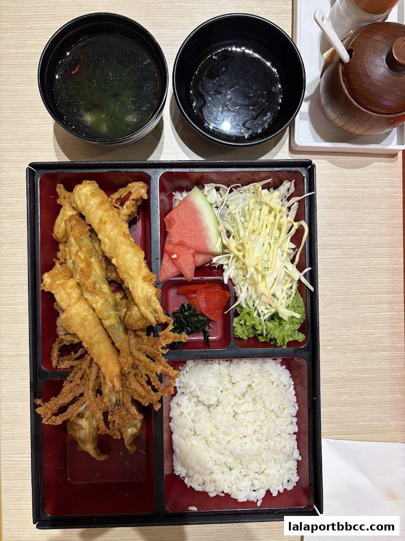 A bento box meal with tempura, rice, salad, watermelon, and soup.
