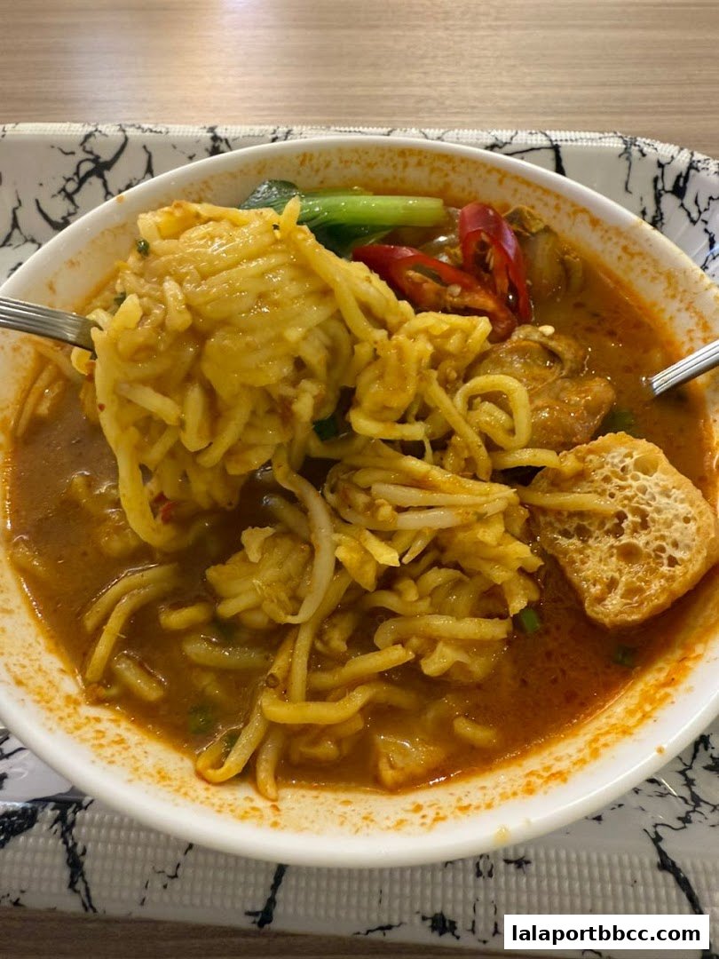 A close-up of a delicious bowl of noodles with broth, chili, and vegetables.