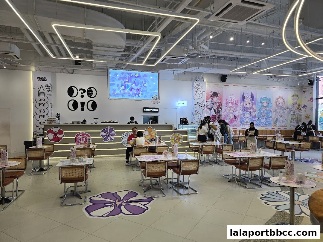 Interior of a brightly lit cafe with anime-style decorations and seating.