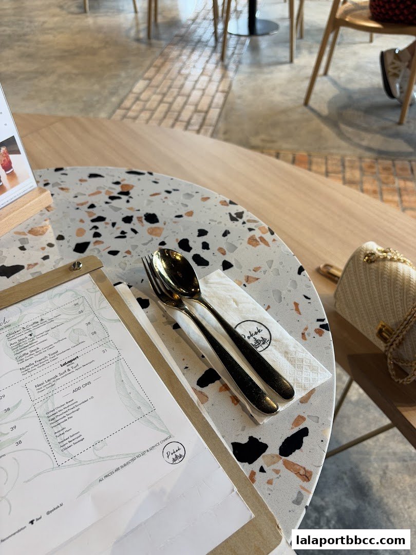 A table setting at POKOK LaLaport with a menu, cutlery, and a napkin.