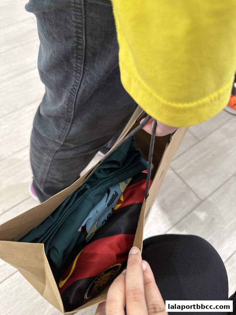 A person holding a shopping bag filled with Puma branded clothing.