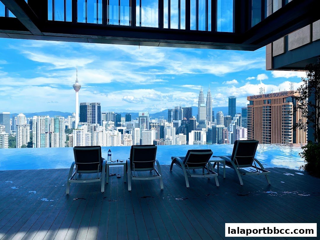 Infinity pool with lounge chairs overlooking a city skyline with skyscrapers and a tower.