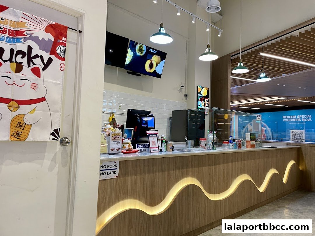 The interior of a modern shop with a wooden counter, display screens, and a 'No Pork, No Lard' sign.