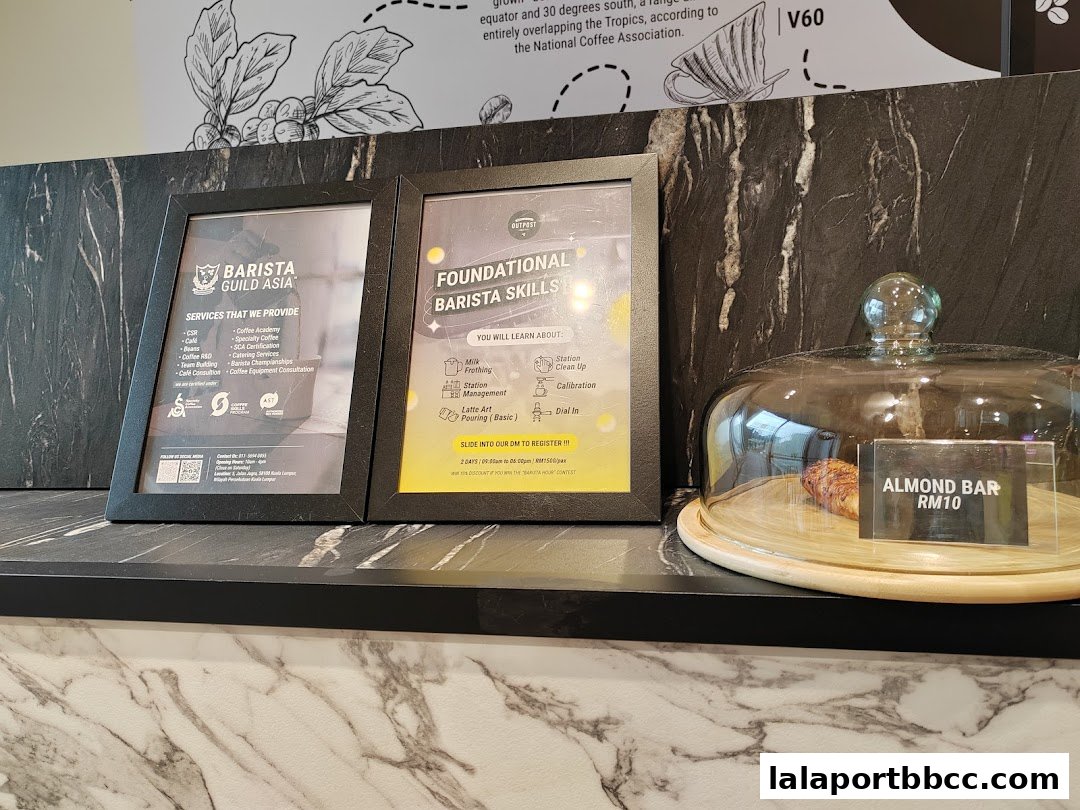 Framed notices about barista skills and services next to an almond bar under a glass dome.