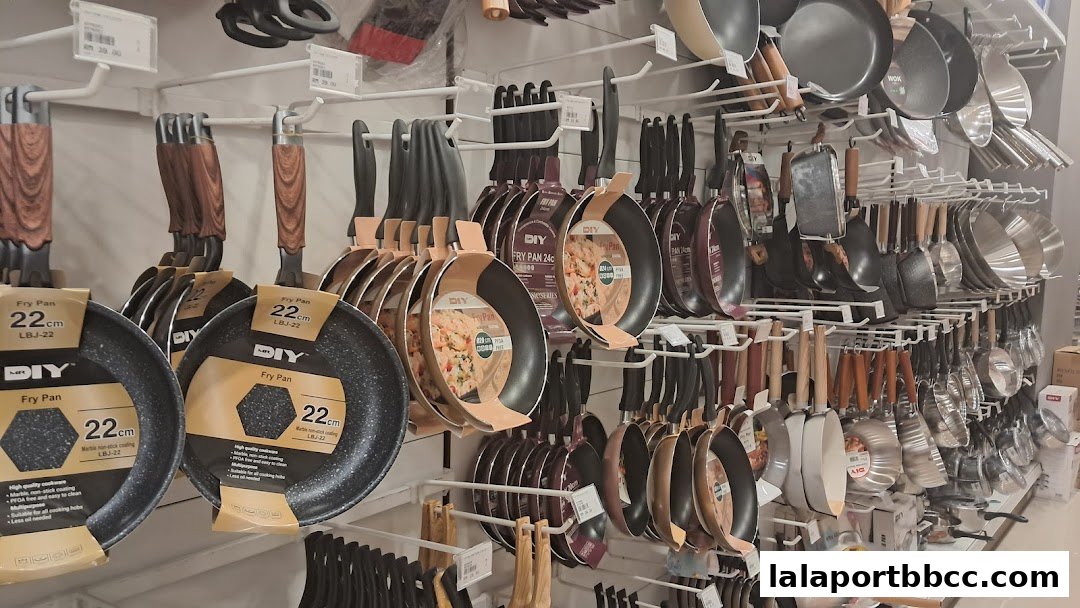 A display of various frying pans and kitchen utensils on shelves in a retail store.