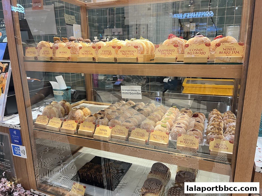 A display case filled with various sweet pastries and donuts, showcasing different flavors and toppings.